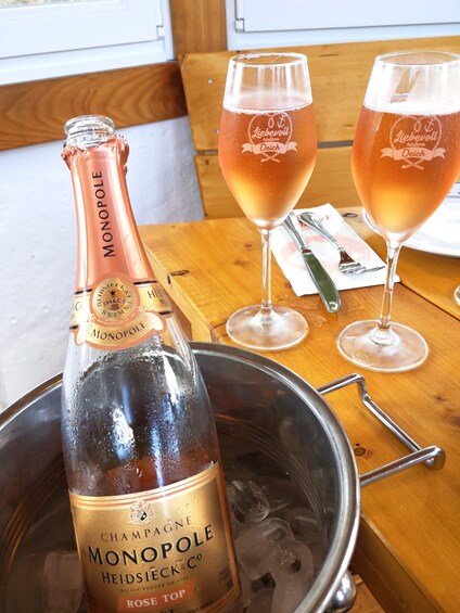 A bottle of champagne and two glasses on a wooden table. 5