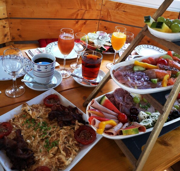 A wooden table with breakfast items, including eggs, bacon, and various fruits and cheeses. 2
