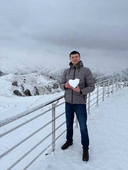 A person holding a snowball on a snowy mountain path. 5
