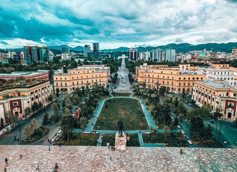 A cityscape with a central square, surrounding buildings, and distant mountains. 5