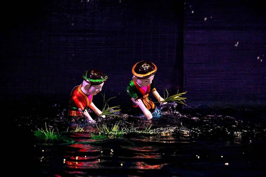 Two figures in traditional attire, one with a green headband, engaged in an activity near water. 2