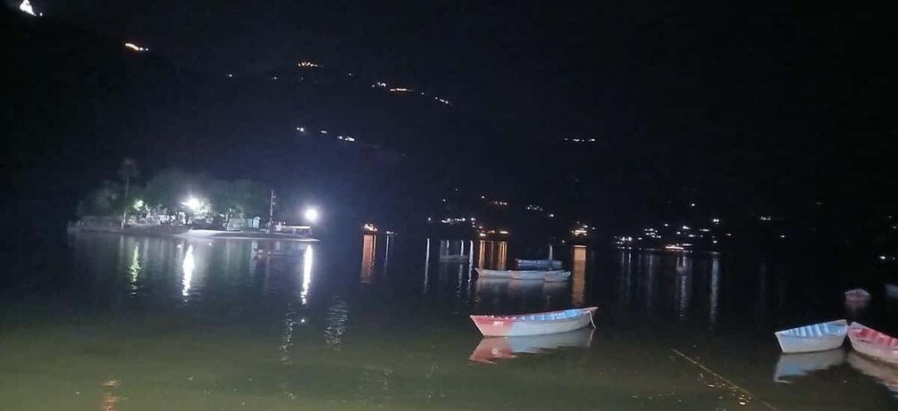 A nighttime scene with boats docked at a pier, illuminated by nearby lights. 2