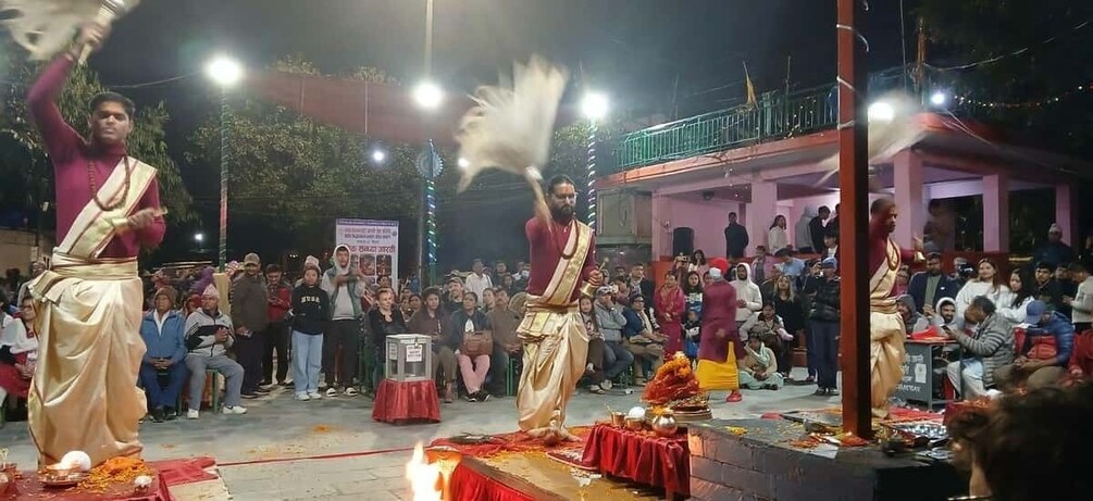 Two men performing a ritual with a fire on a stage in front of a crowd. 3