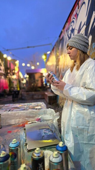 A person painting on a wall with spray paint cans and a palette. 1