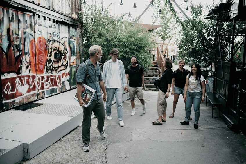 A group of people walking on a street with graffiti on the walls. 3