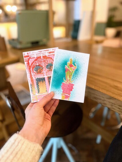 A person holding two colorful cards with abstract designs. 5