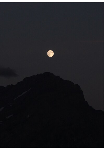 A full moon rising above a mountain range. 2