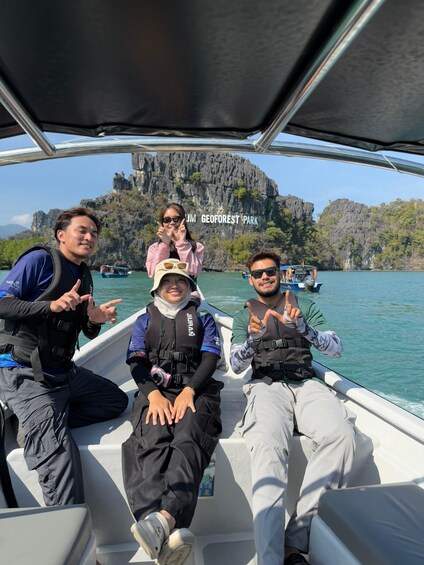 A group of people on a boat with a rocky landscape and cliffs in the background. 1