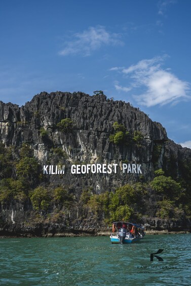 A boat on water with a rocky cliff and greenery in the background labeled 'Kilim GeoForest Park.' 3