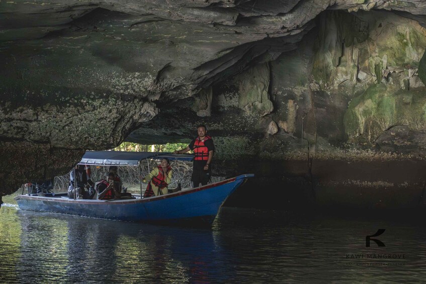 A boat with people wearing life jackets near a cave entrance. 4