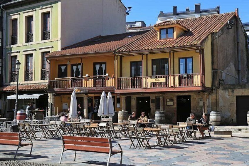 A café with outdoor seating, a balcony, and a building with a red-tiled roof. 3