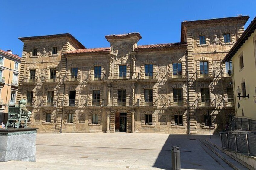 A historic stone building with multiple balconies and a central entrance. 1