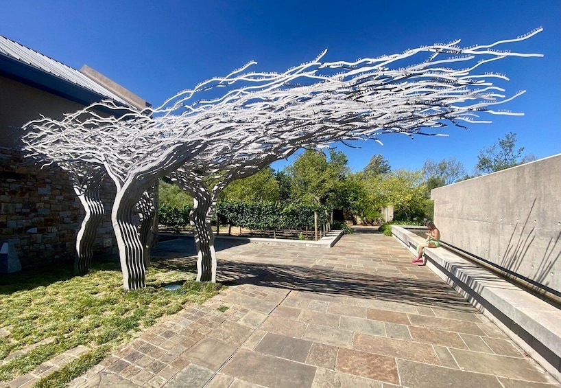 A garden with a unique white tree sculpture and stone pathways. 2