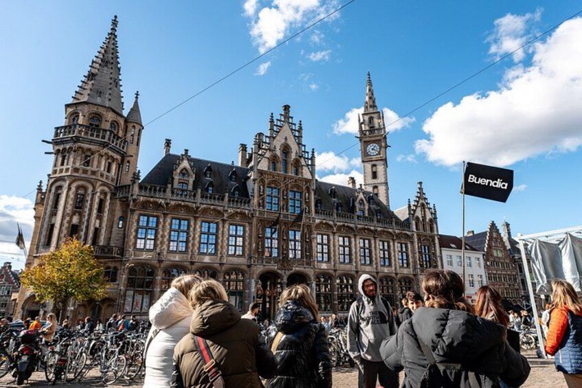 A historic building with a clock tower, a flag reading 'Buendia,' and a crowd of people in front. 2