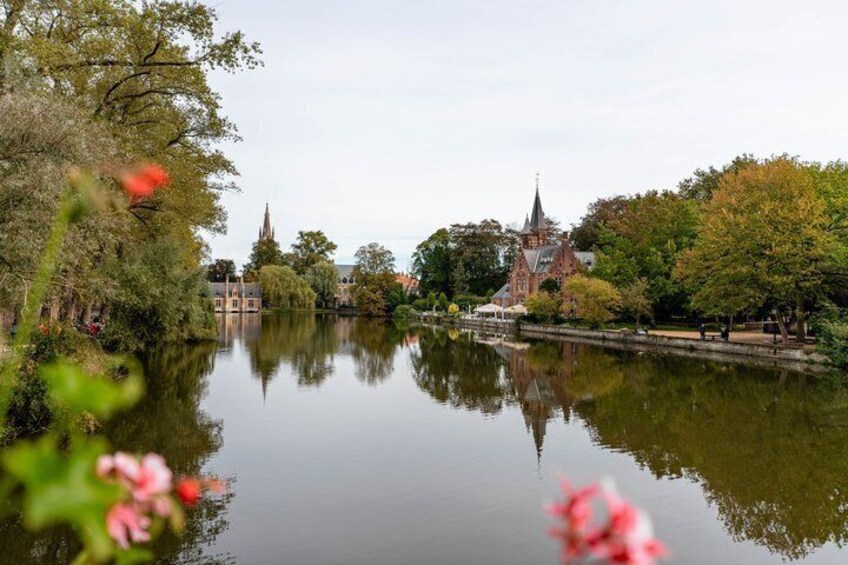 A calm river reflecting a historic building, surrounded by trees and a clear sky. 4