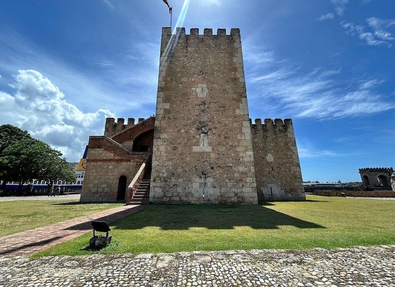 A historic stone tower with a staircase leading up to a door, surrounded by a grassy area and a cobblestone path. 4