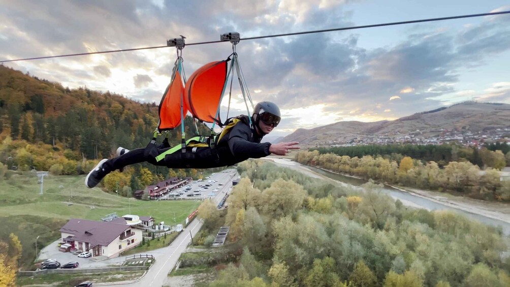 A person bungee jumping with a harness and parachute, with a landscape of trees, a river, and a town below. 1