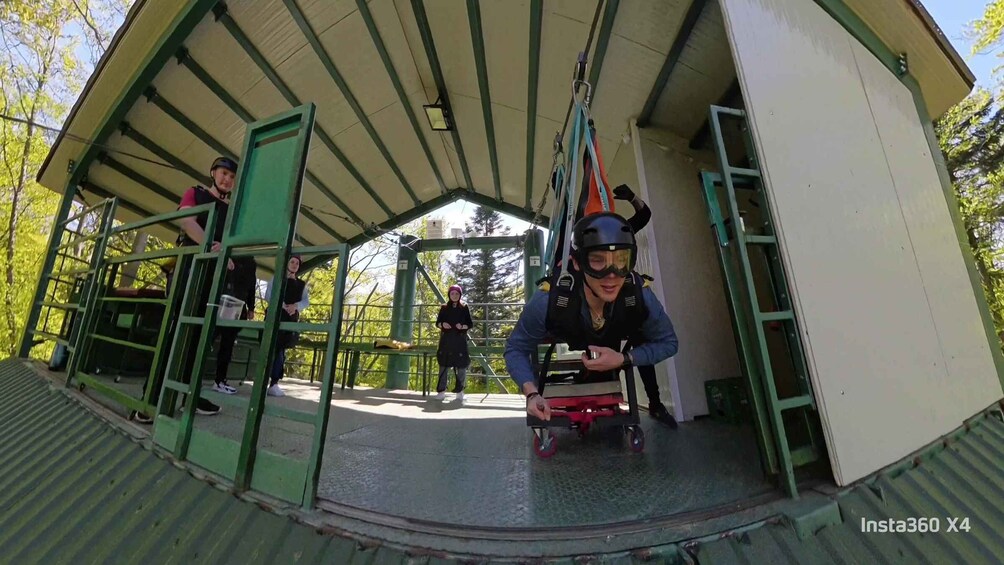 A covered outdoor area with a metal roof, green railings, and a person in a helmet preparing to ride a small red vehicle. 5