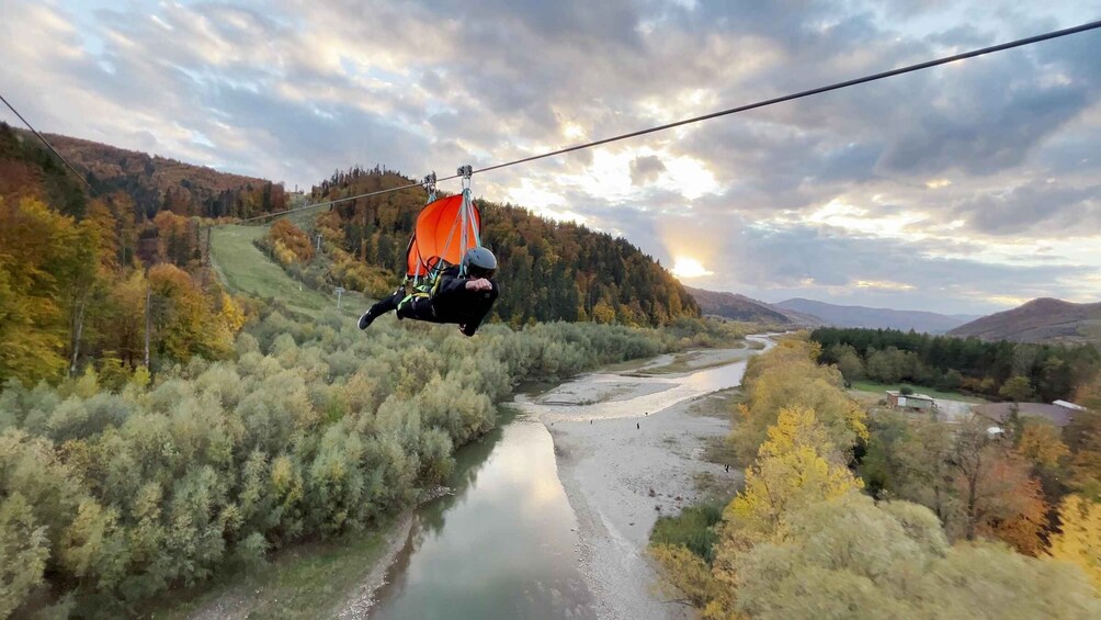A person suspended on a cable, a river, and autumn-colored trees. 4