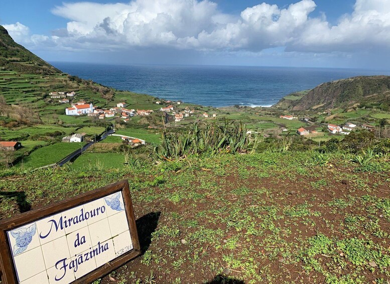 A coastal village with terraced fields and a sign reading 'Miradouro da Fajãzinha.' 2