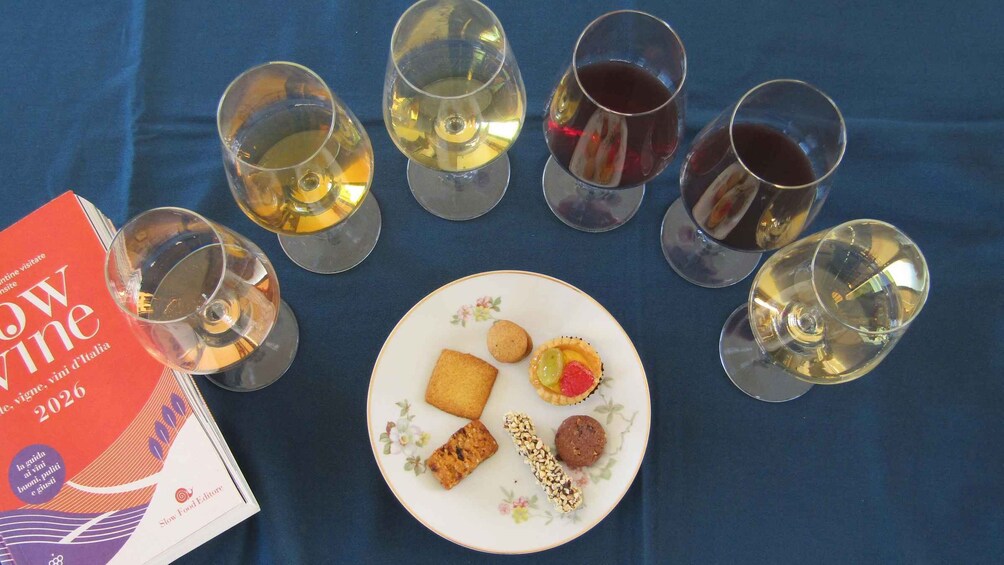 A table with wine glasses, a plate of food, and a book titled 'Slow Wine 2026'. 4