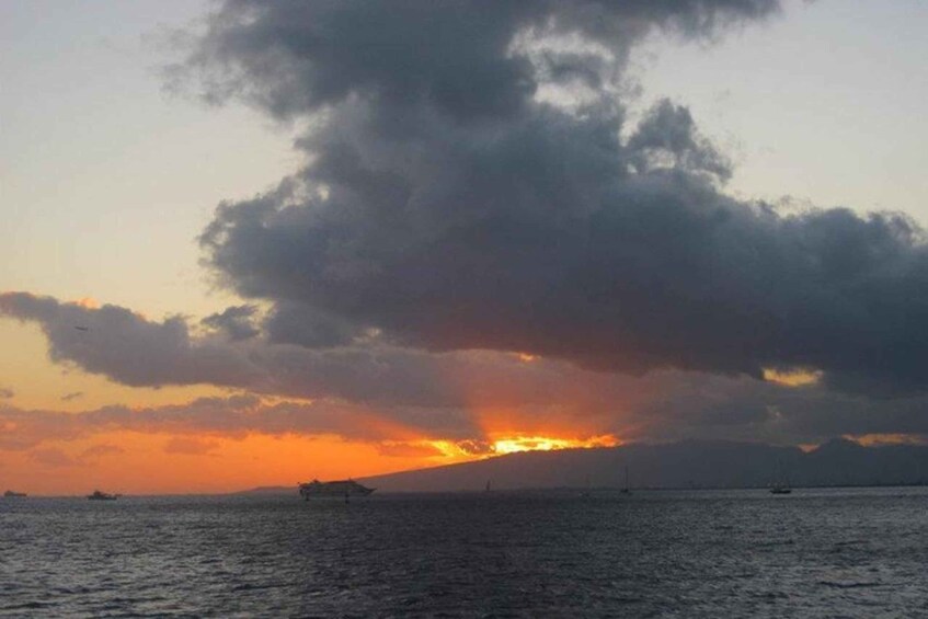 A sunset over a body of water with a ship and a distant mountain. 3