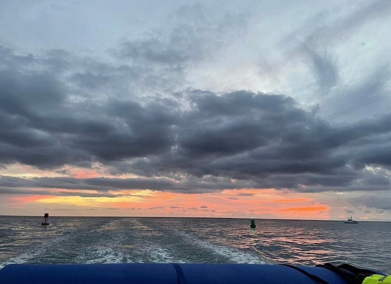 A boat on the ocean with a sunset and overcast sky. 2
