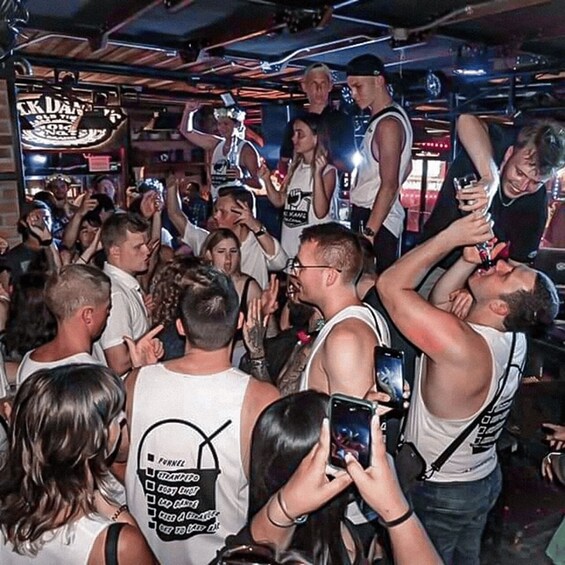 A crowded indoor event with people standing and interacting, some holding drinks. 5