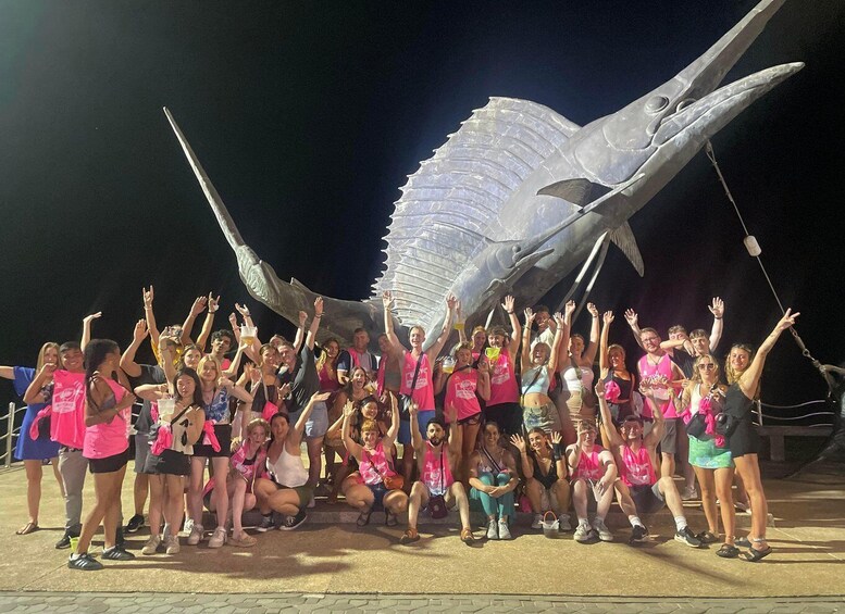 A group of people posing in front of a large sculpture of a fish. 1