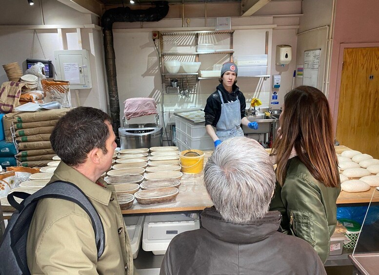 A bakery with bread on display and a person in an apron behind the counter. 4