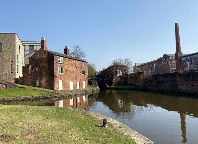 A canal with brick buildings, a bridge, and a tall chimney. 3