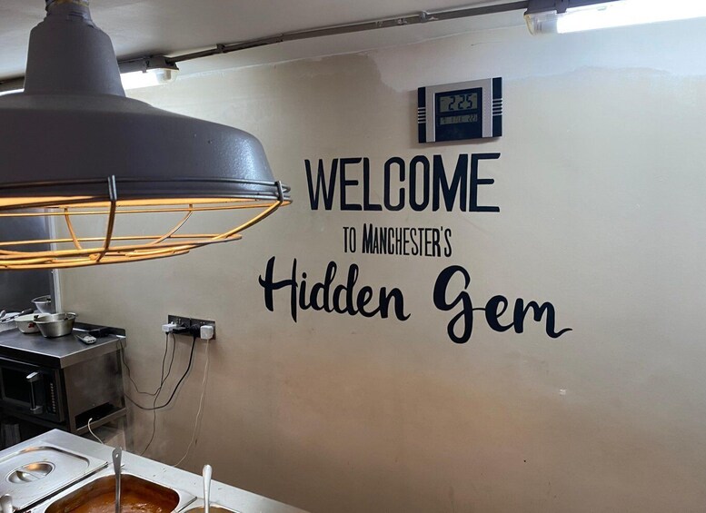 A wall with the text 'WELCOME TO MANCHESTER'S Hidden Gem' and a digital clock displaying 22:25. 5