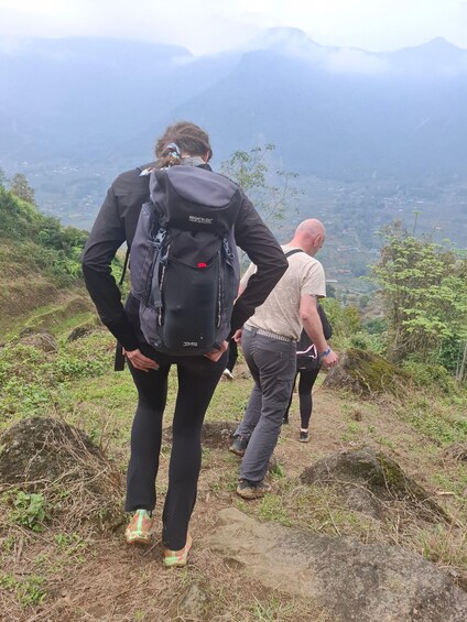 Two hikers on a mountain trail with a scenic view of a valley and mountains in the background. 5