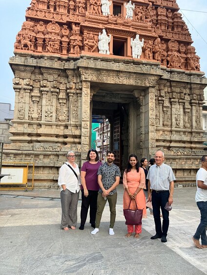A group of people standing in front of a temple with intricate carvings and statues. 3