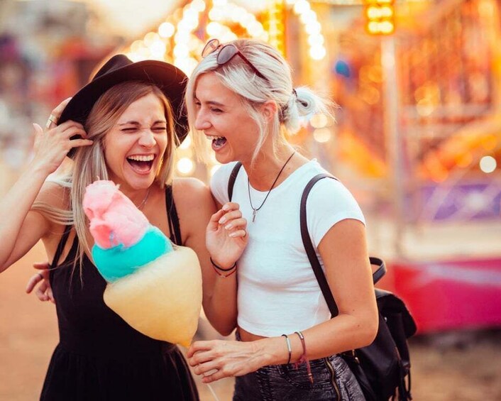 Two people holding a colorful cotton candy at a fairground. 5