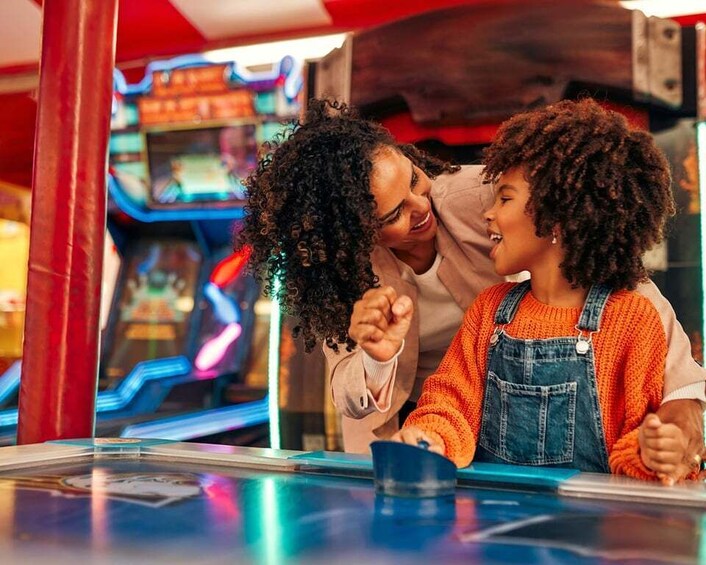 Two people playing a video game at an arcade. 2