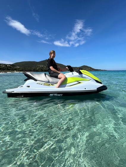 A person on a jet ski over clear water with a hilly landscape in the background. 4