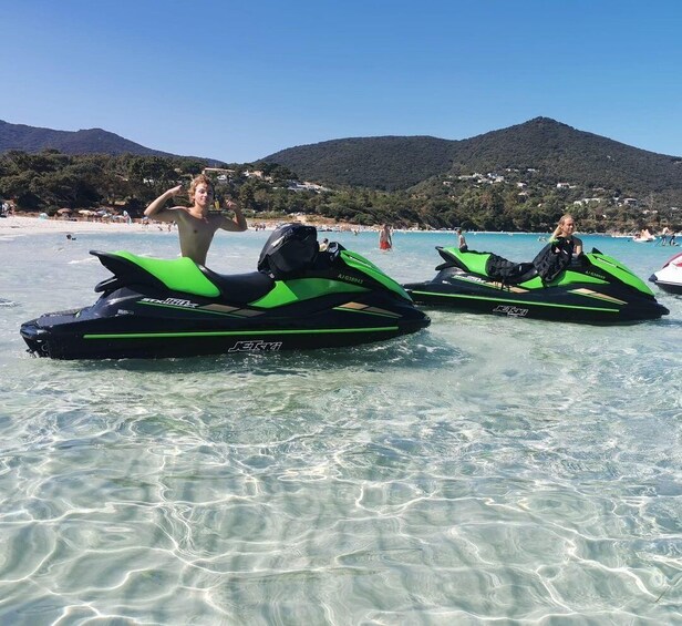 Two jet skis on a clear beach with a mountainous backdrop. 2