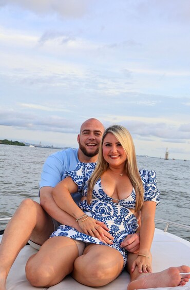 Two people on a boat with a water body and distant structures in the background. 4