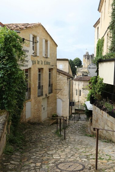 A narrow cobblestone street flanked by historic buildings with signage for restaurants. 5