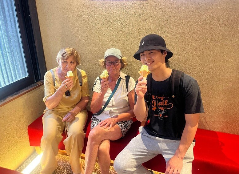 Three people sitting on a bench, each holding an ice cream cone. 4