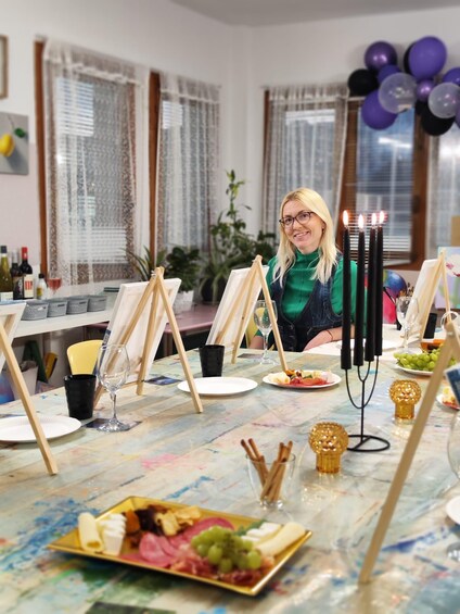 A woman at a table with a plate of food, wine glasses, and candles. 3