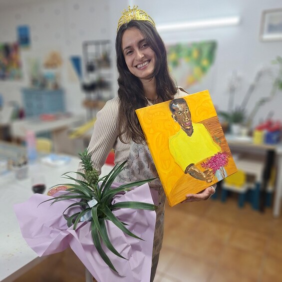 A person holding a painting and a plant. 2