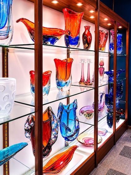 A display of colorful glass vases on shelves. 3