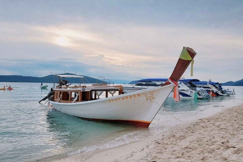 A boat with a number on its side, docked at a beach with other boats in the background. 5