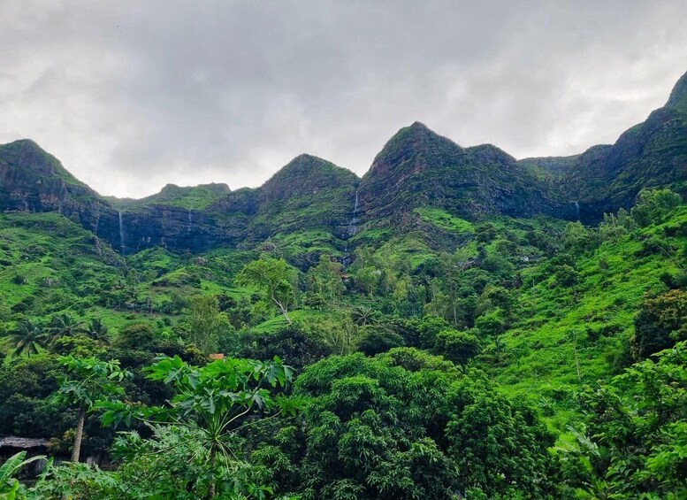 A lush green valley with steep mountains and waterfalls. 4