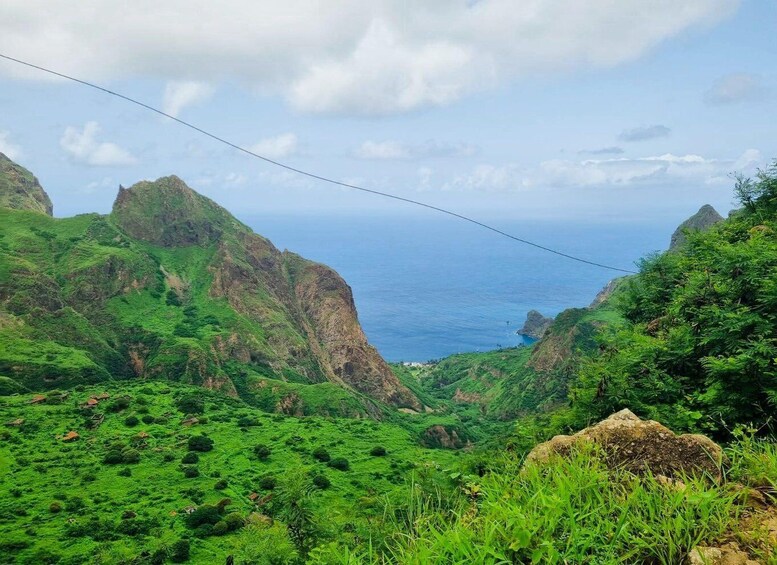 A lush green valley with steep cliffs and a view of the ocean. 3