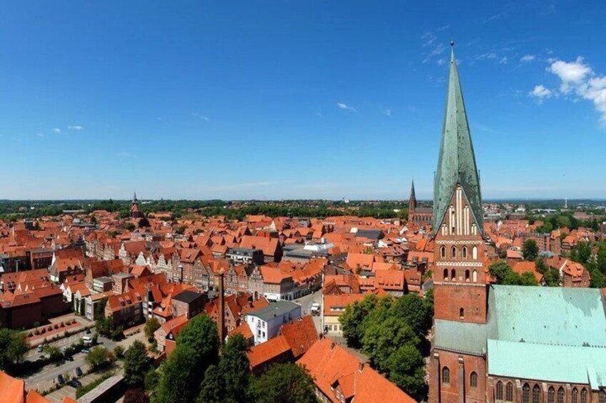 A town with red-roofed buildings, a prominent church with a tall spire, and a clear blue sky. 4