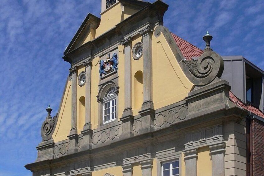 A yellow building with a clock tower, ornate decorations, and a red roof. 5