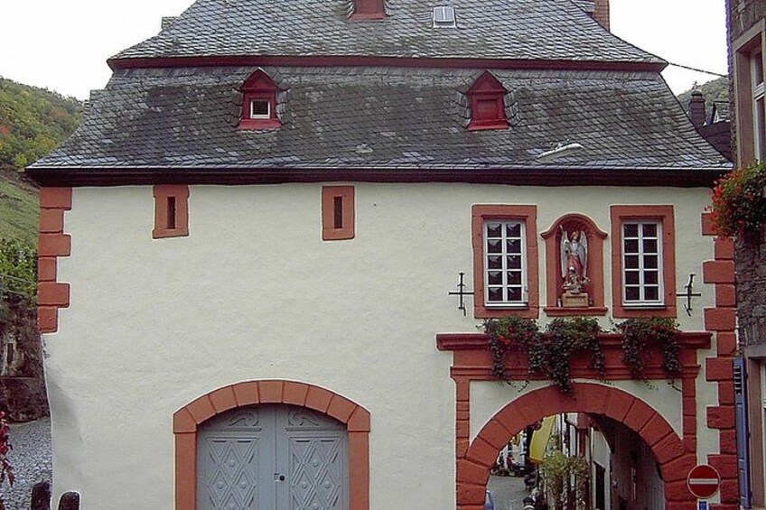 A building with a white facade, red brick accents, a grey door, and a small statue above the entrance. 3